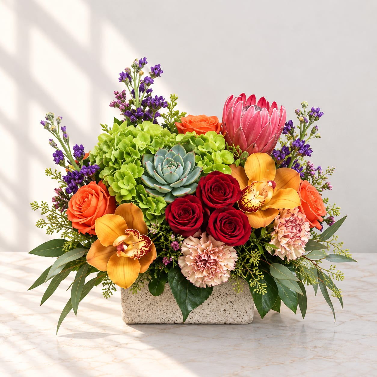 Mixed bouquet in a stone rectangular vase with roses, orchids, and succulents