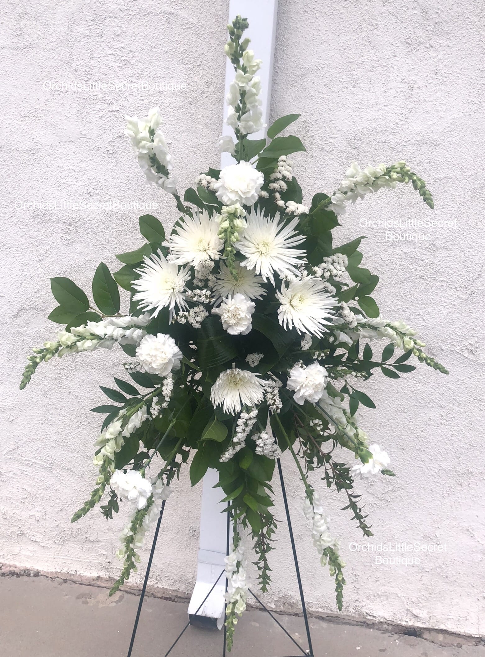 White floral standing spray on a black easel