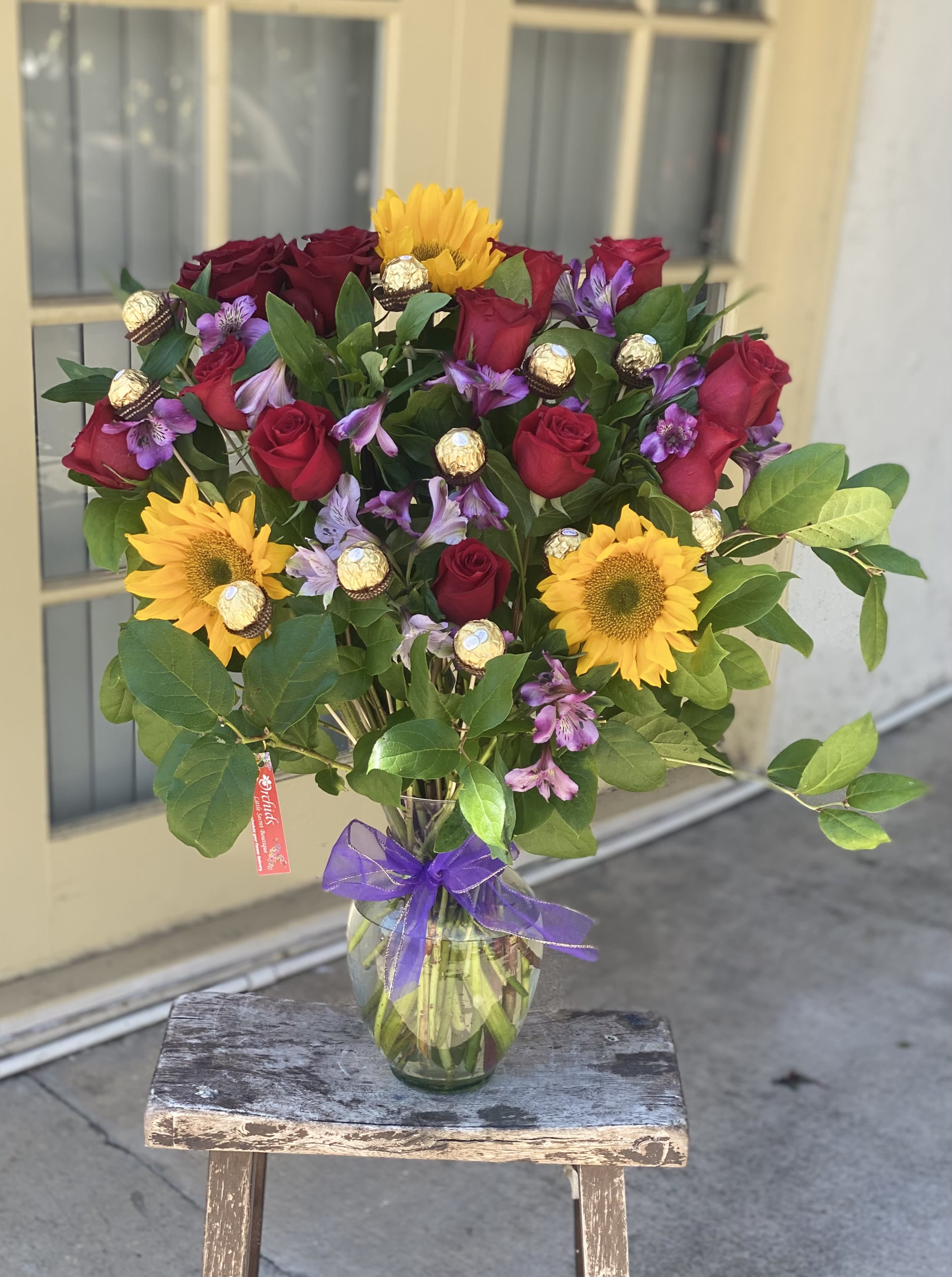 Bouquet of red roses and yellow sunflowers in a glass vase
