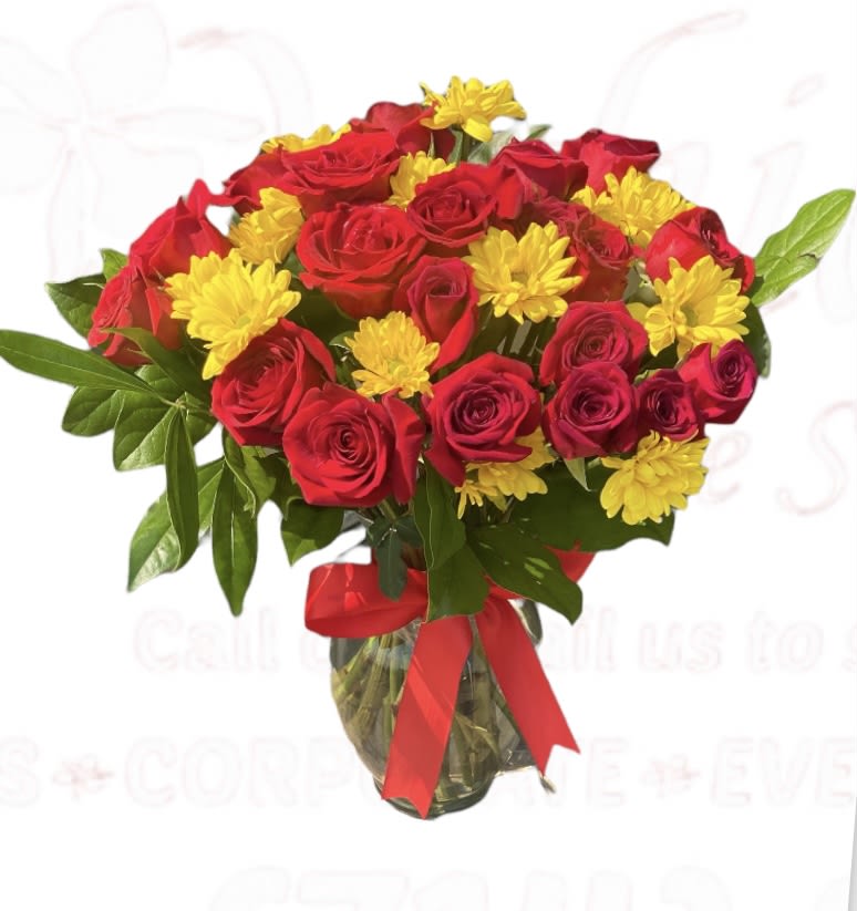 Bouquet of red roses and yellow daisies in a glass vase with a red ribbon