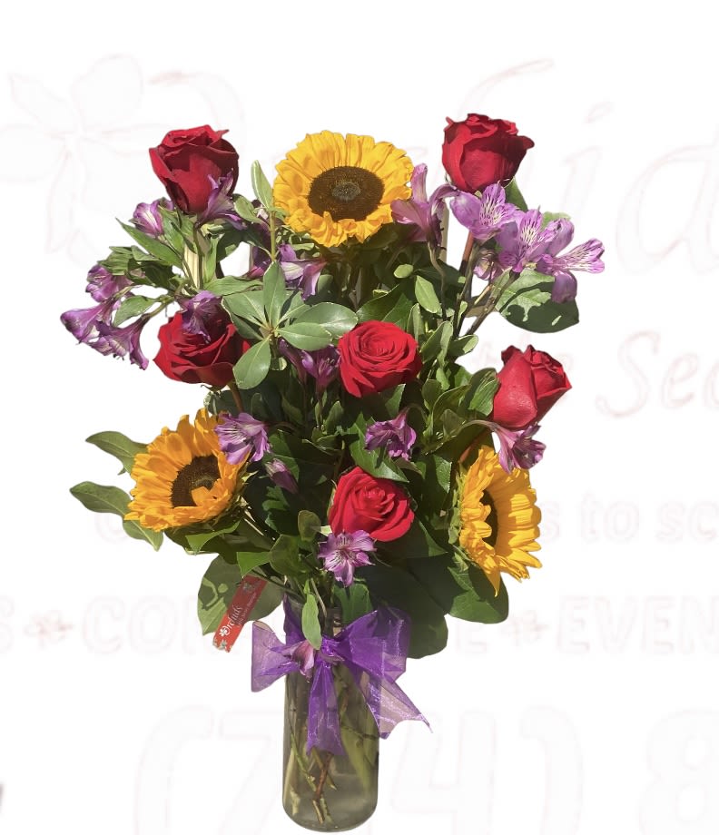Bouquet of red roses and sunflowers in a glass vase with a purple ribbon