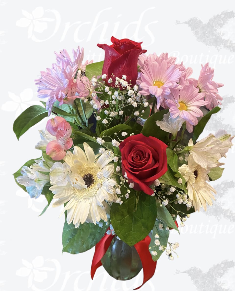 Bouquet of red roses, pink daisies, and white gerbera daisies in a vase
