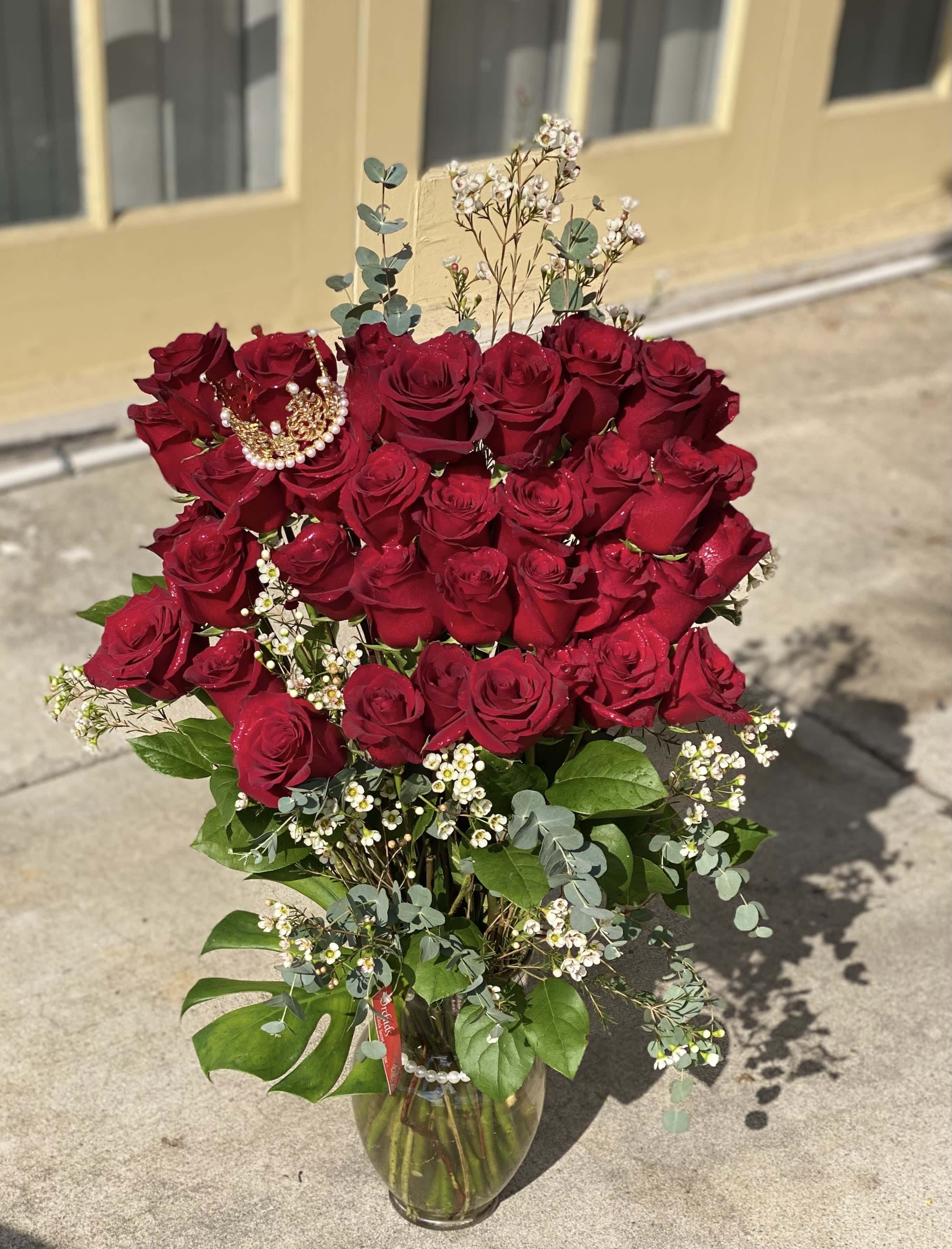 Bouquet of red roses in a glass vase with small white filler flowers