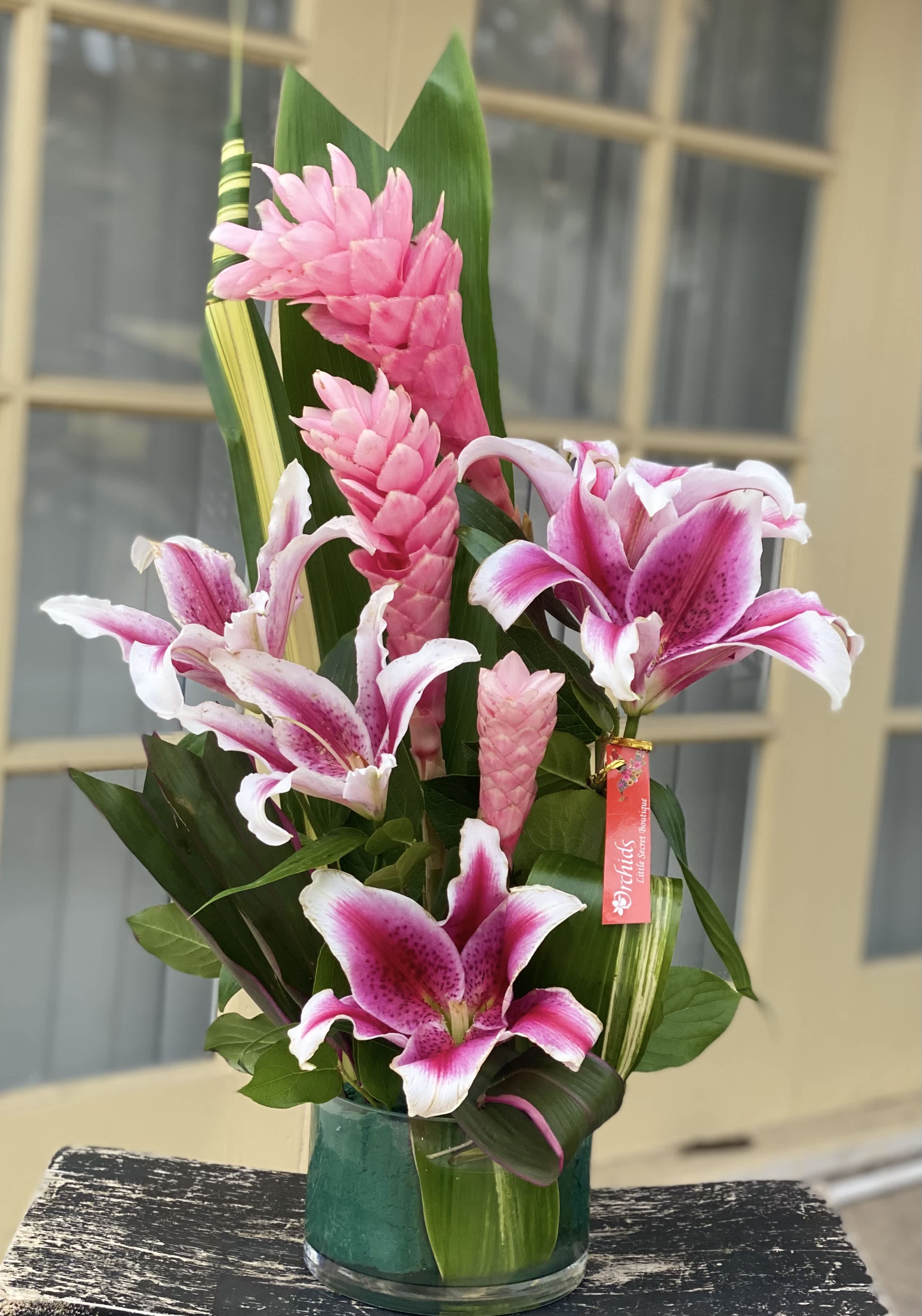 Pink lilies and tropical blooms in a glass vase