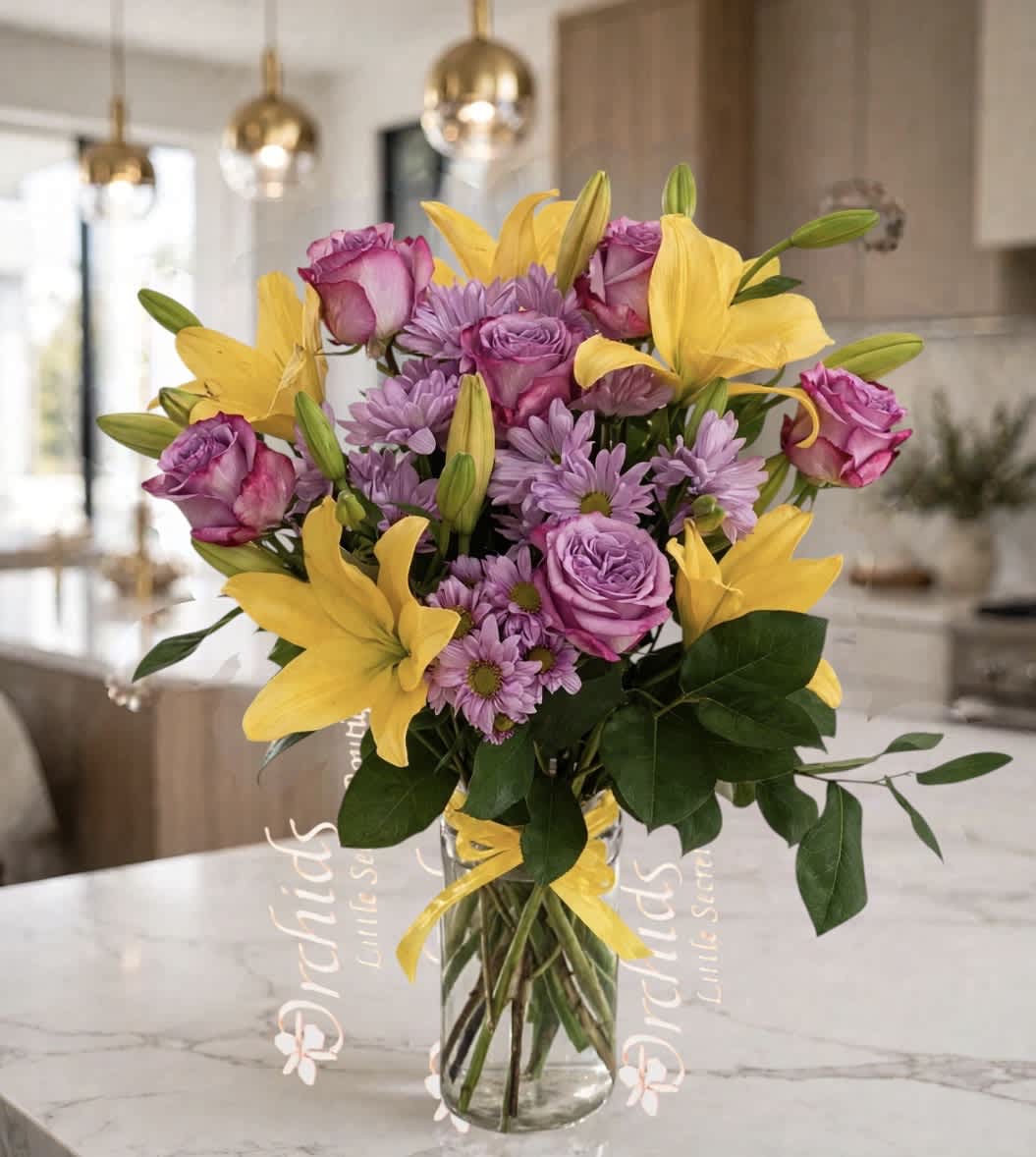 Bouquet of yellow lilies, purple roses, and lavender daisies in a glass vase