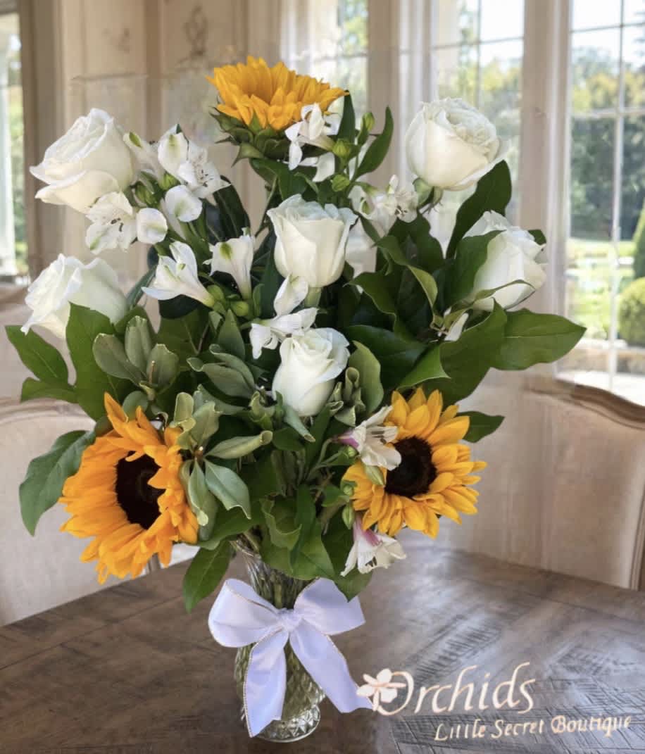 Bouquet of white roses, white alstroemeria, and sunflowers in a glass vase