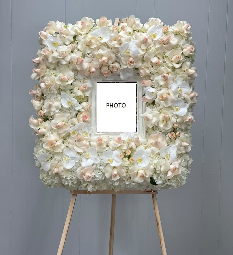 Floral photo frame covered in white and blush orchids on an easel