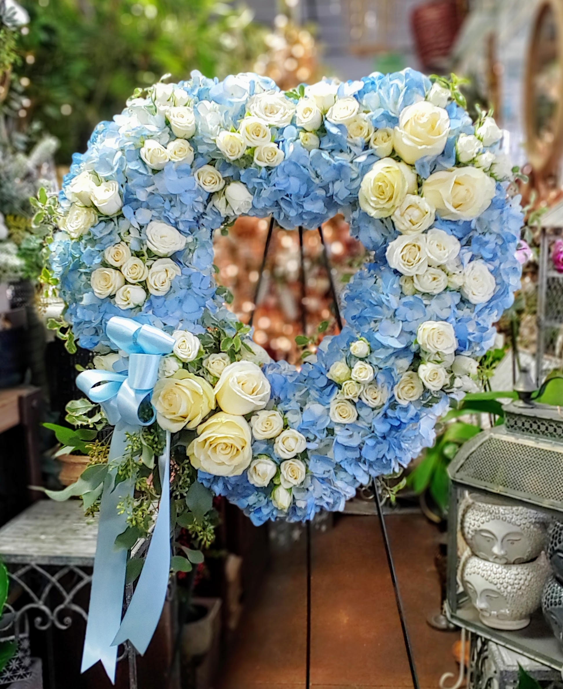 Heart-shaped wreath of blue hydrangeas and white roses on a stand