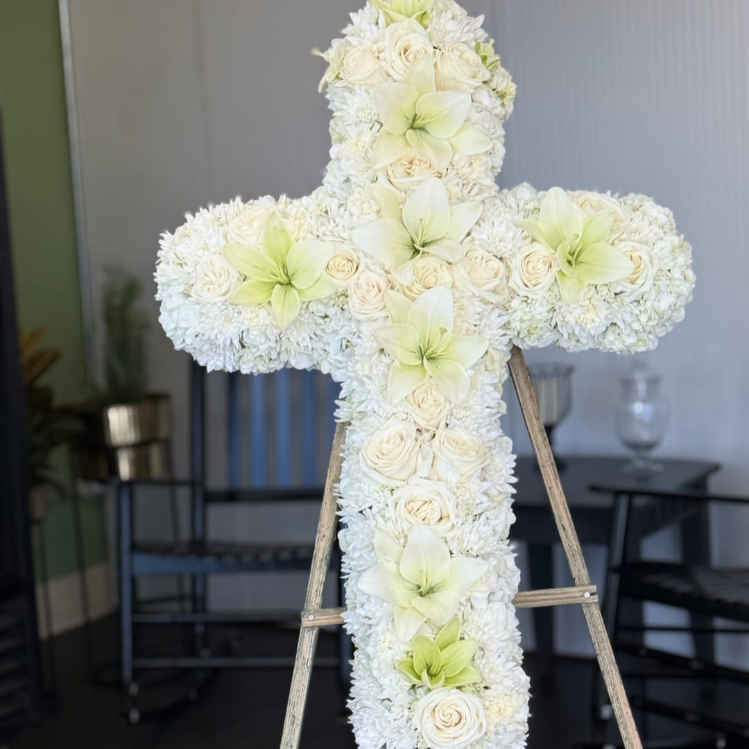 White floral cross on a wooden stand with pale green accents
