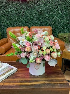 Large pastel bouquet in a white hatbox on a wooden table