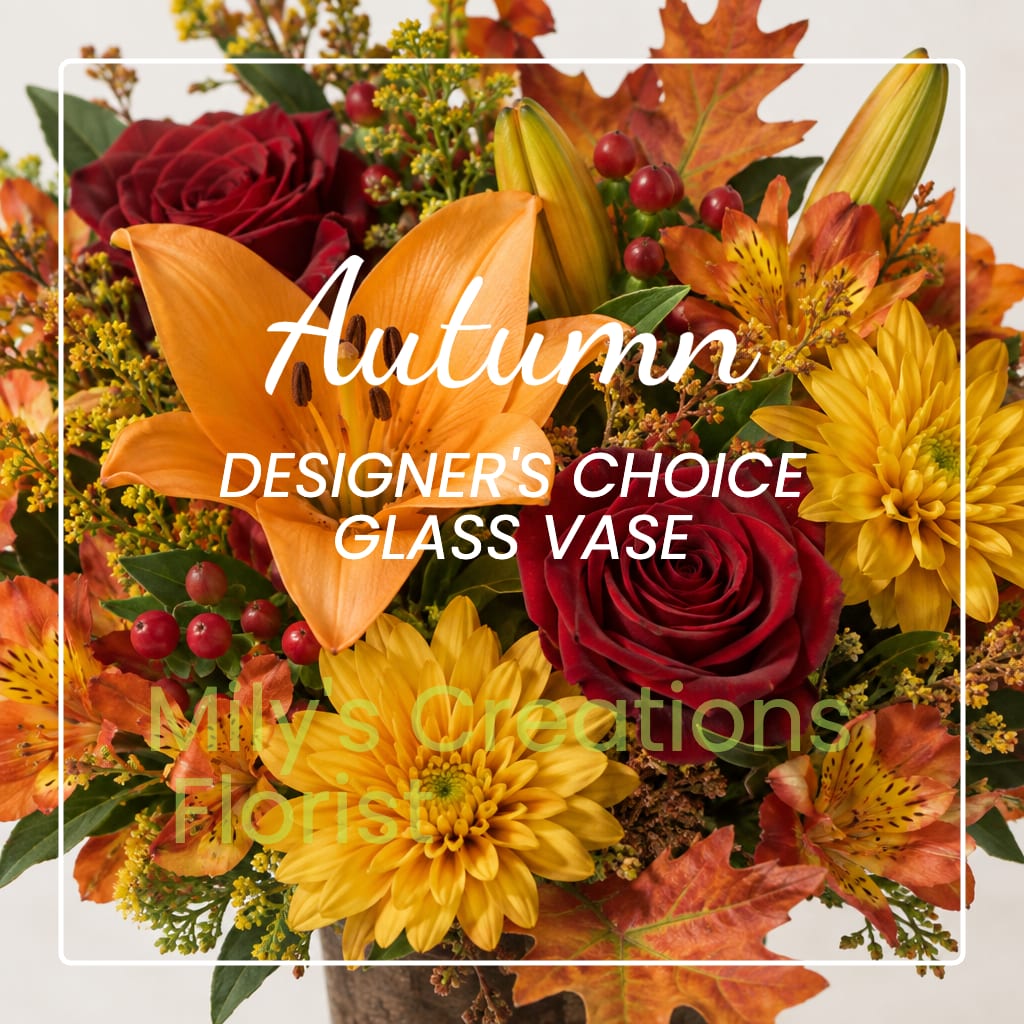 Autumn bouquet with red roses, orange lilies, and yellow daisies in a glass vase