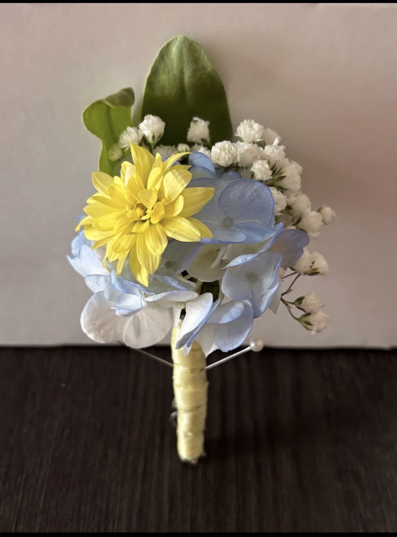 Small boutonniere with yellow and blue flowers and white accents
