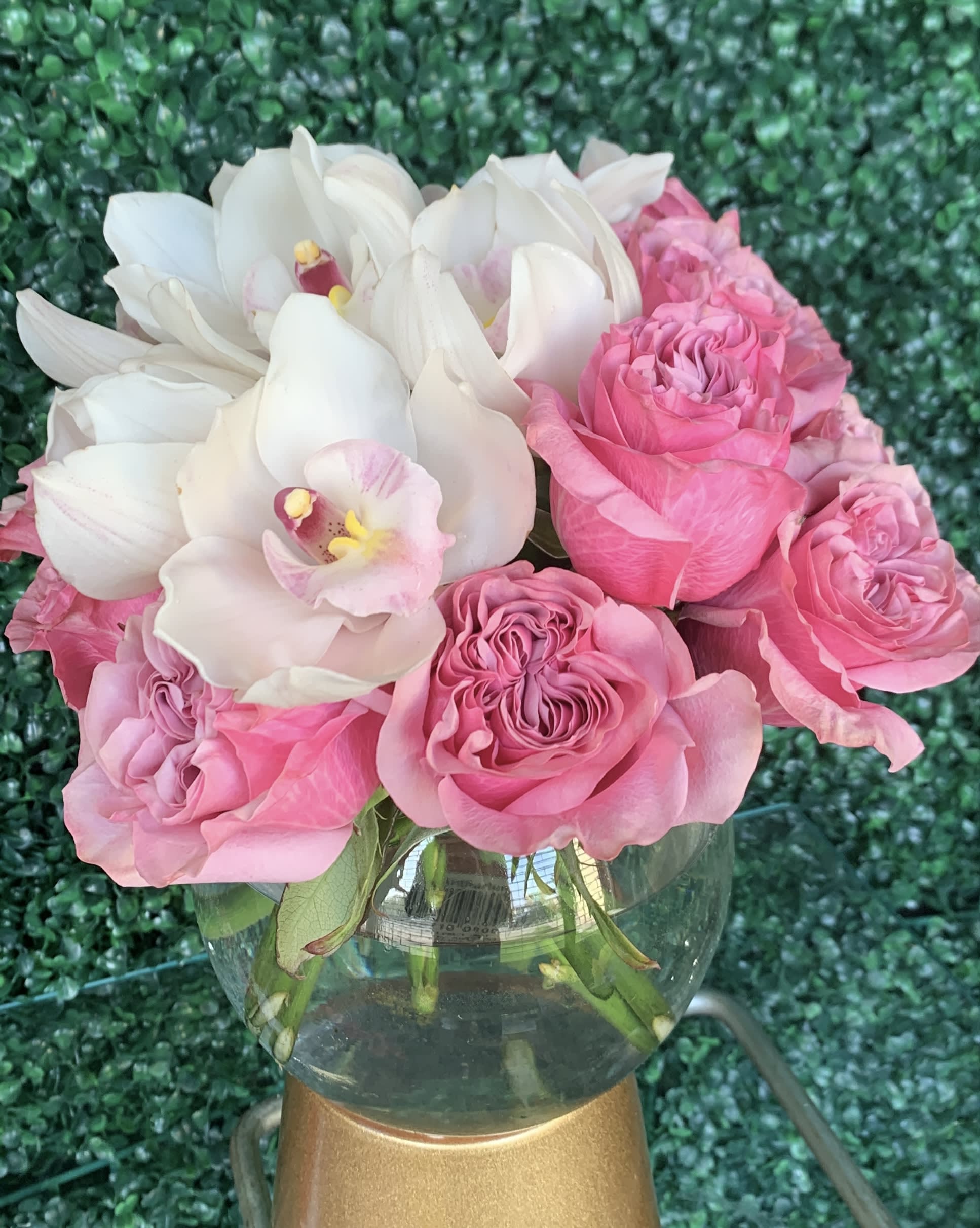 Pink roses and white orchids arranged in a glass vase