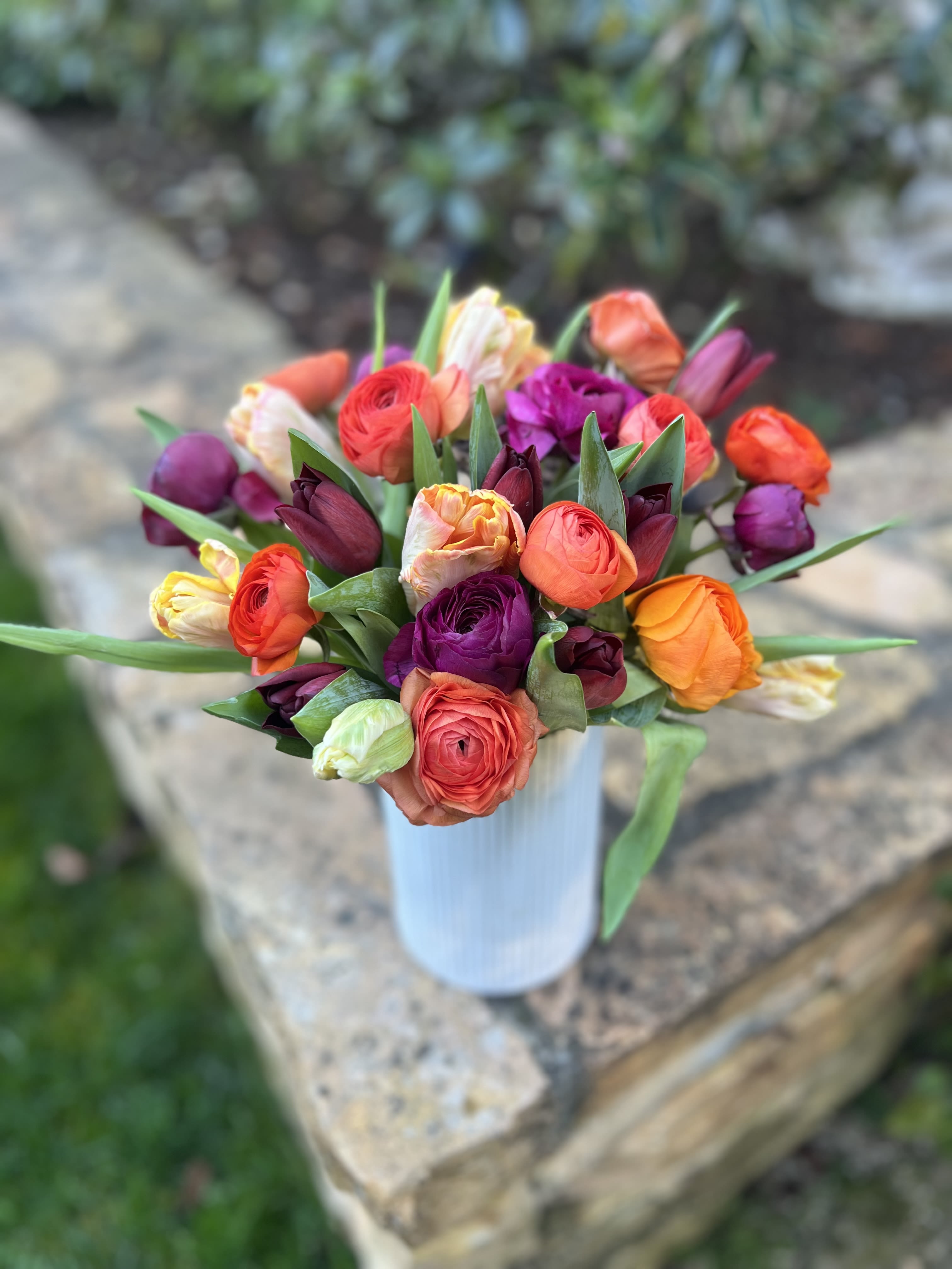 Beets and Carrots  - Gorgeous local ranunculus and tulips in shades of orange, coral, plum and cranberry to create a striking color palette for this Spring! Pictured is the standard version of 30 mixed stems. 