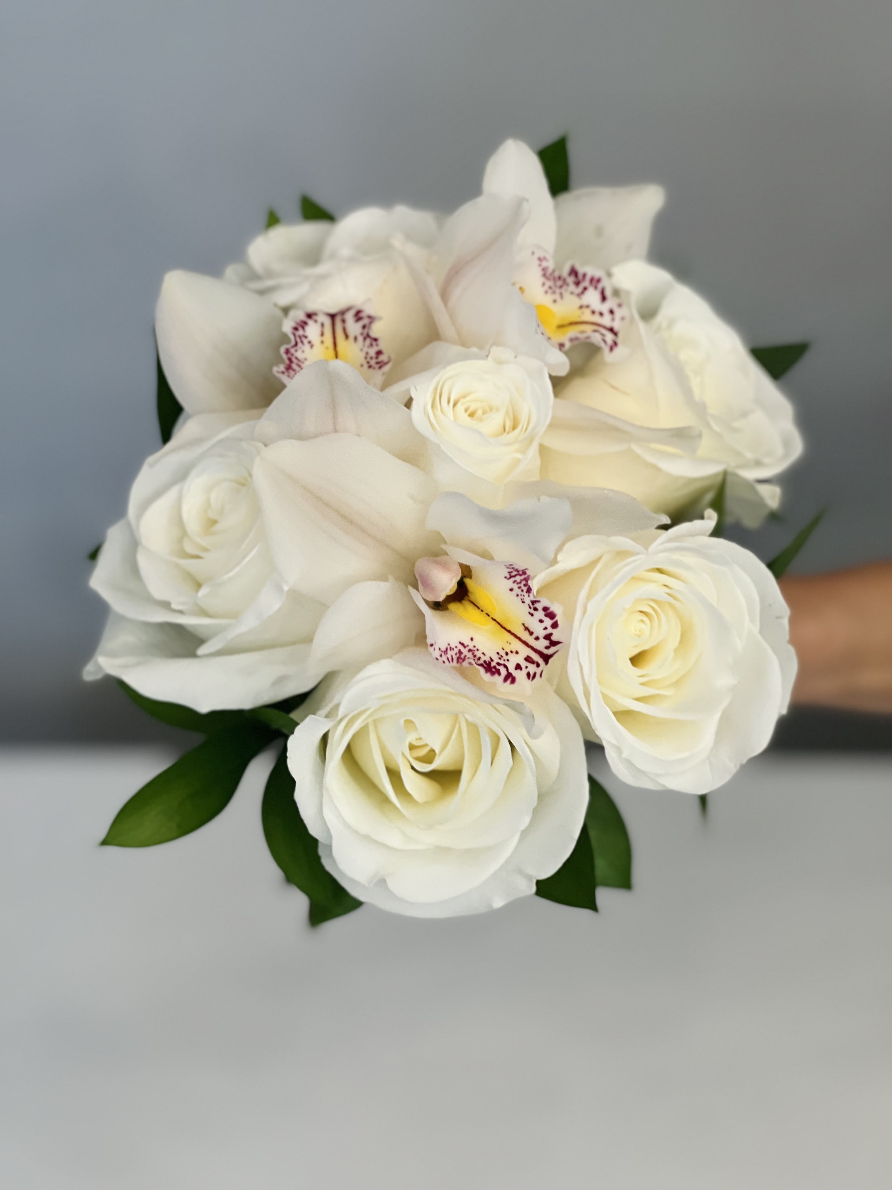 White rose and orchid bouquet with green leaves