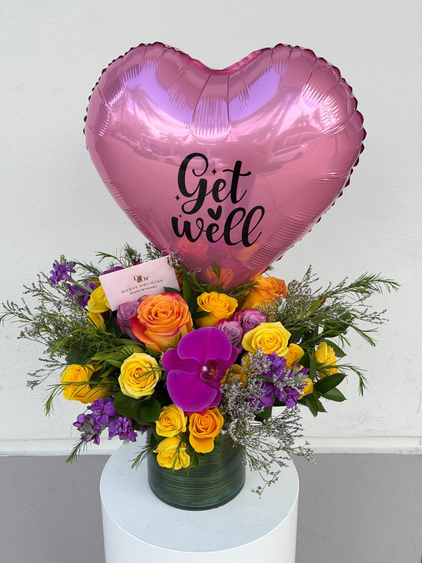 Pink heart balloon above a colorful rose bouquet in a vase