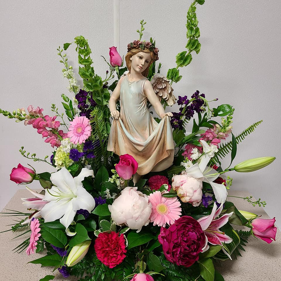 Floral arrangement with a figurine centerpiece and pink, white, and purple flowers