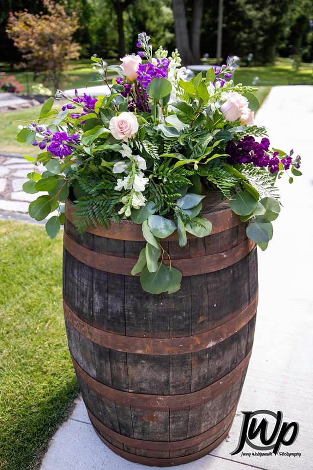 Purple and white floral arrangement in a wooden barrel