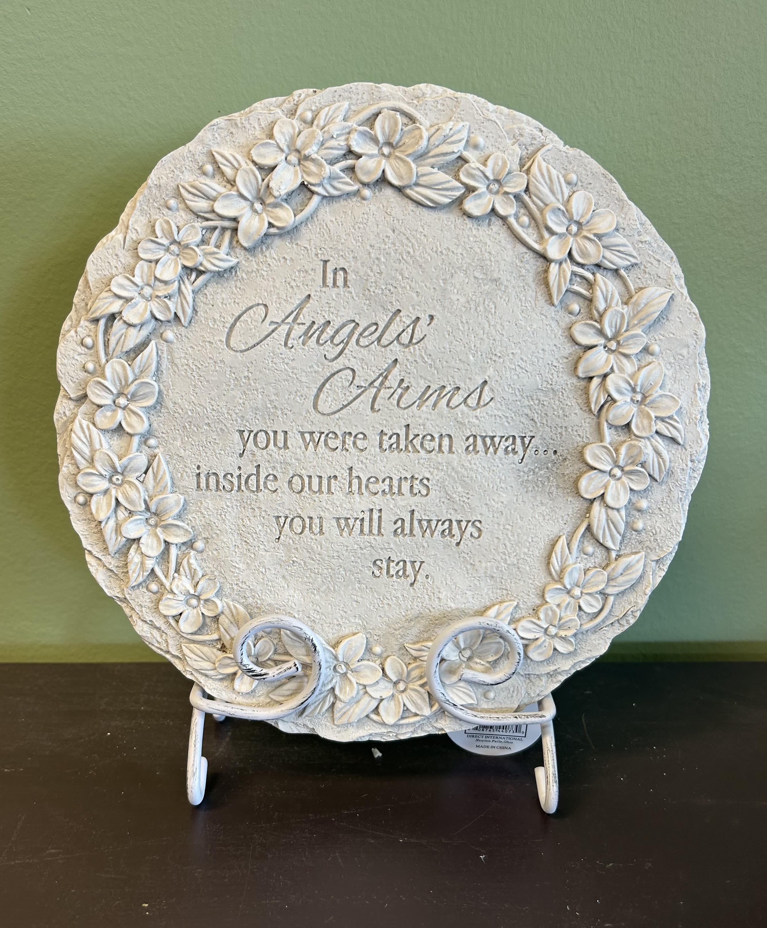 Round memorial plaque with floral relief and an engraved sympathy message