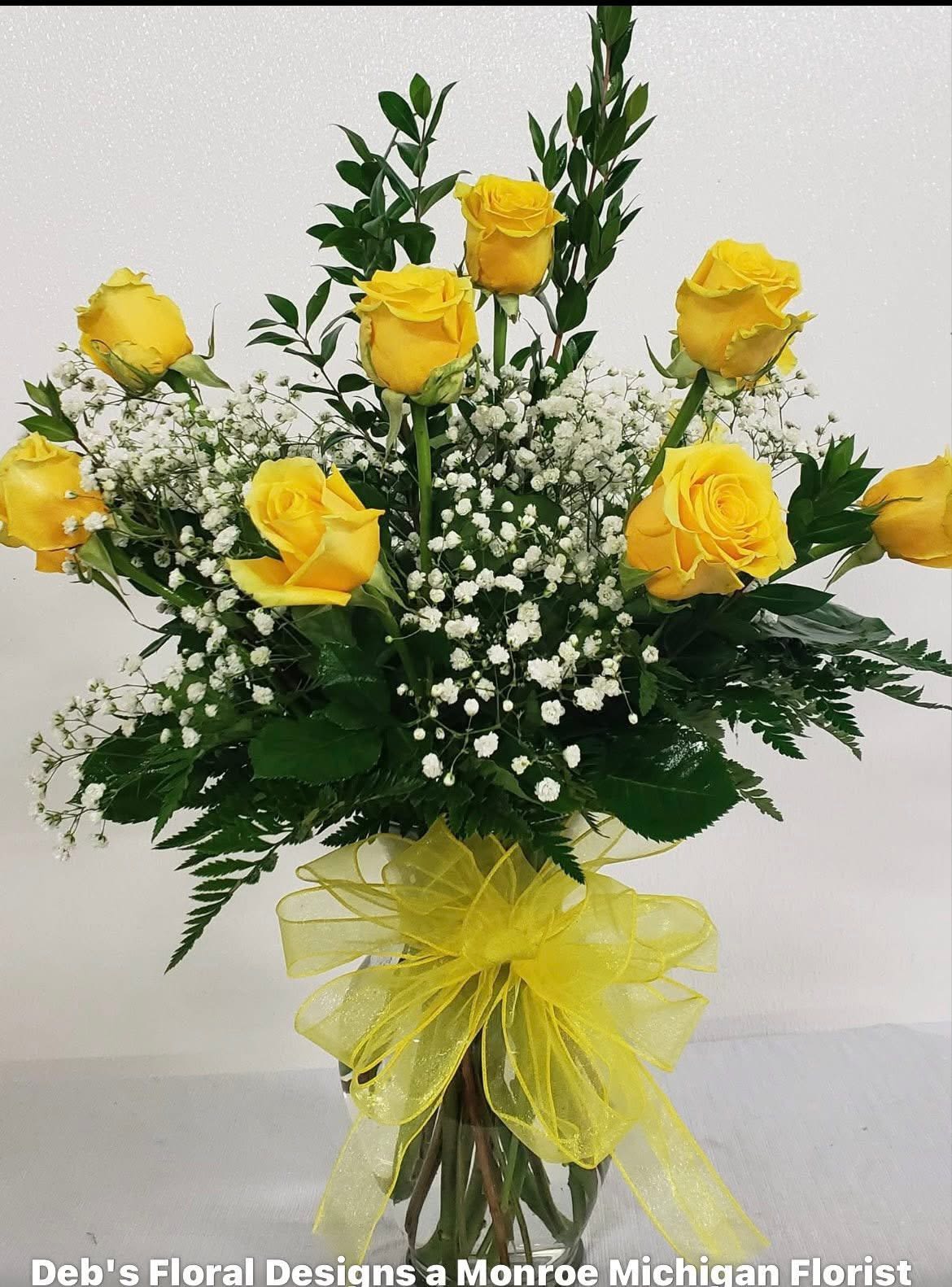Yellow roses with baby's breath in a glass vase tied with a yellow ribbon