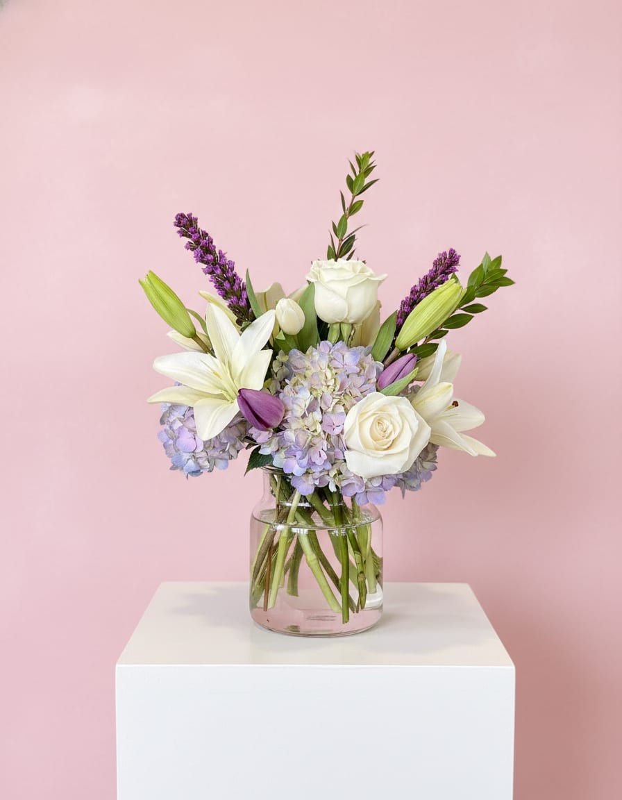 White lilies and roses with lavender hydrangeas in a glass vase