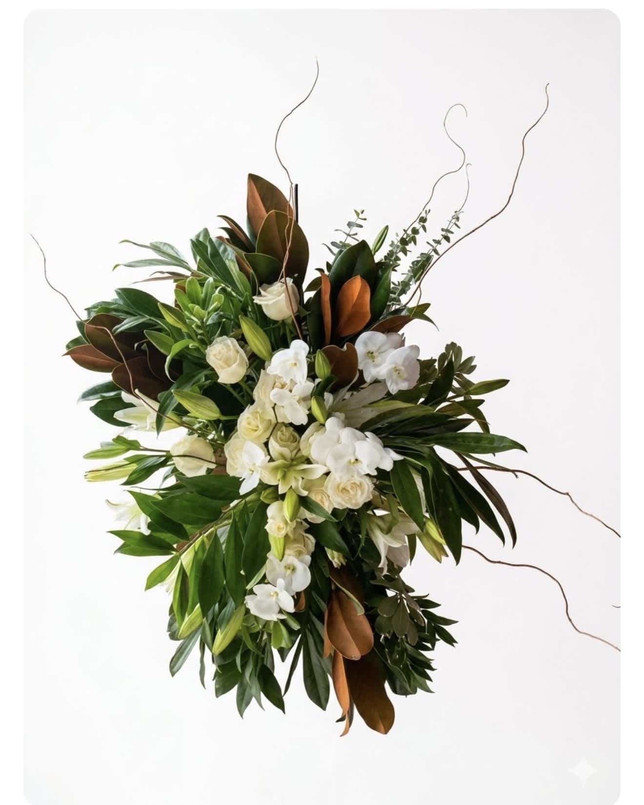 White orchids and cream roses in a lush green arrangement with curly branches