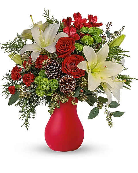 Red and white floral arrangement in a red vase with pinecones
