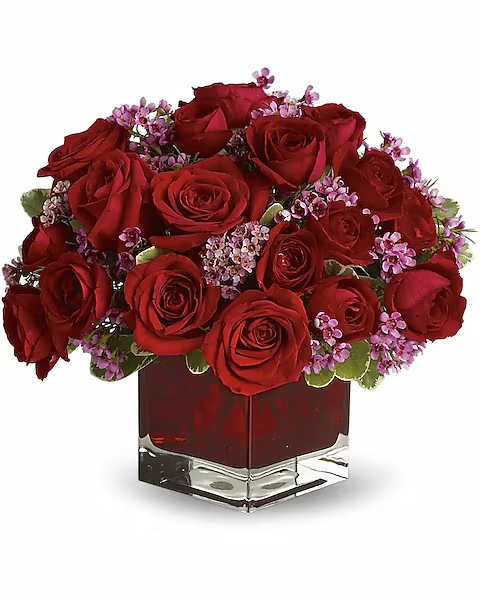 Red roses and purple filler flowers in a square glass vase