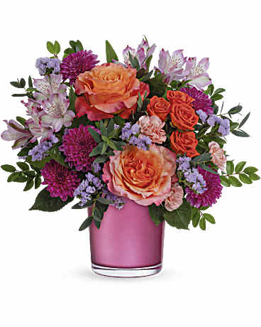 Pink and orange flower arrangement in a pink glass vase