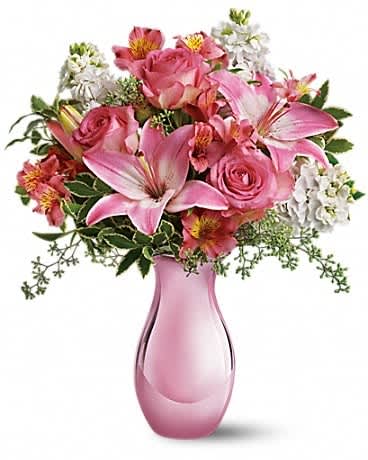 Pink lilies and roses arranged in a pink glass vase