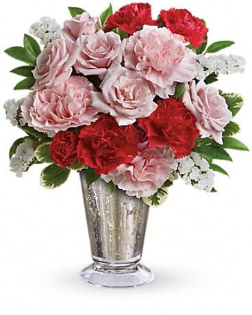 Pink and red carnations with white filler in a silver vase