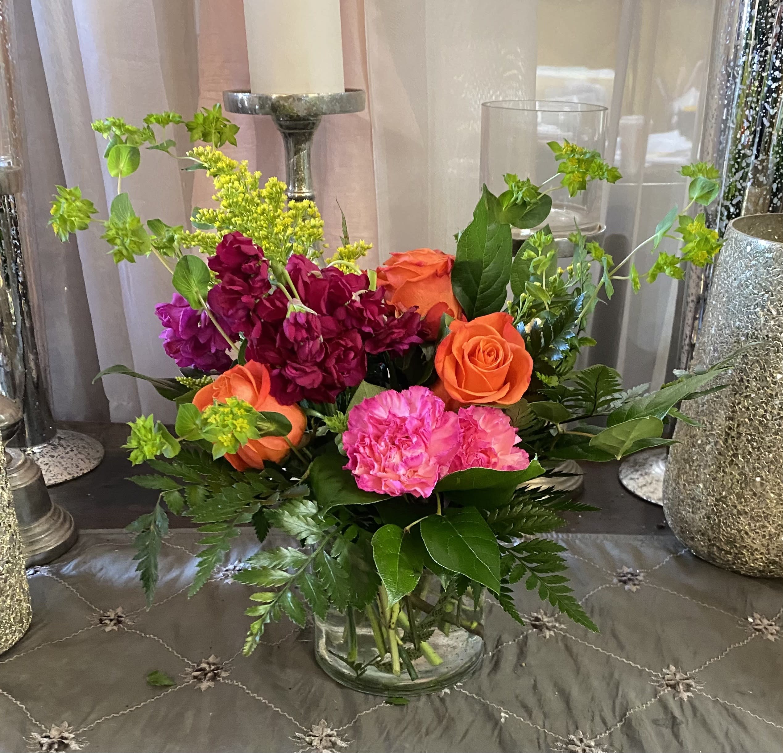 Mixed bouquet of orange and pink flowers in a clear glass vase
