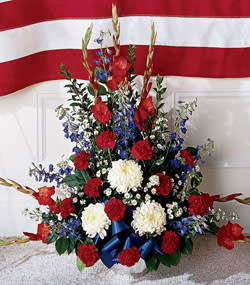Red, white, and blue floral arrangement with ribbon in a vase