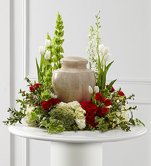 Red roses and white tulips arranged around a beige urn