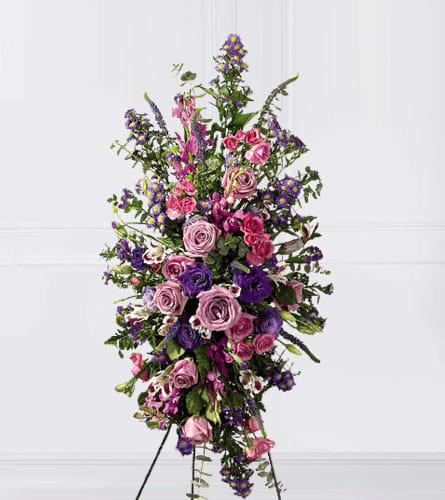 Tall standing spray of pink and purple flowers on a white background