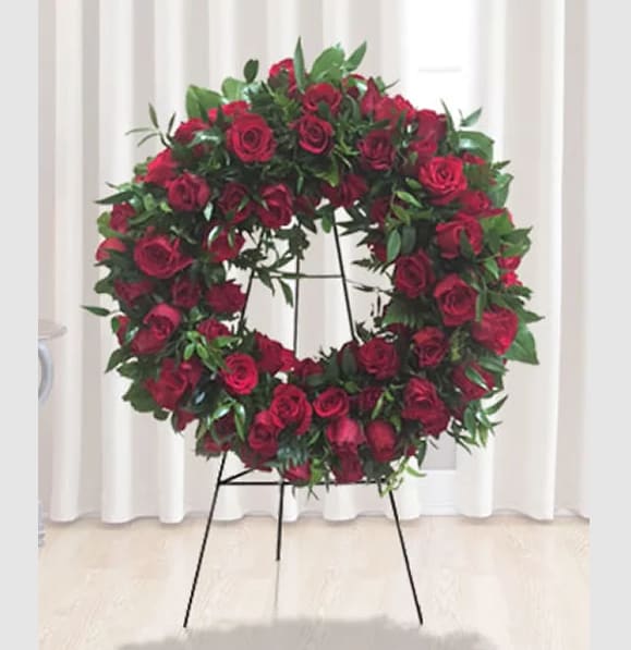 Circular wreath of red roses on a black stand