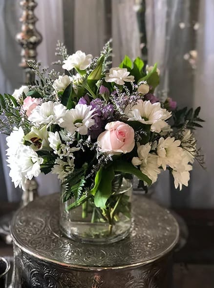 Mixed white, pink, and purple flowers in a clear glass vase