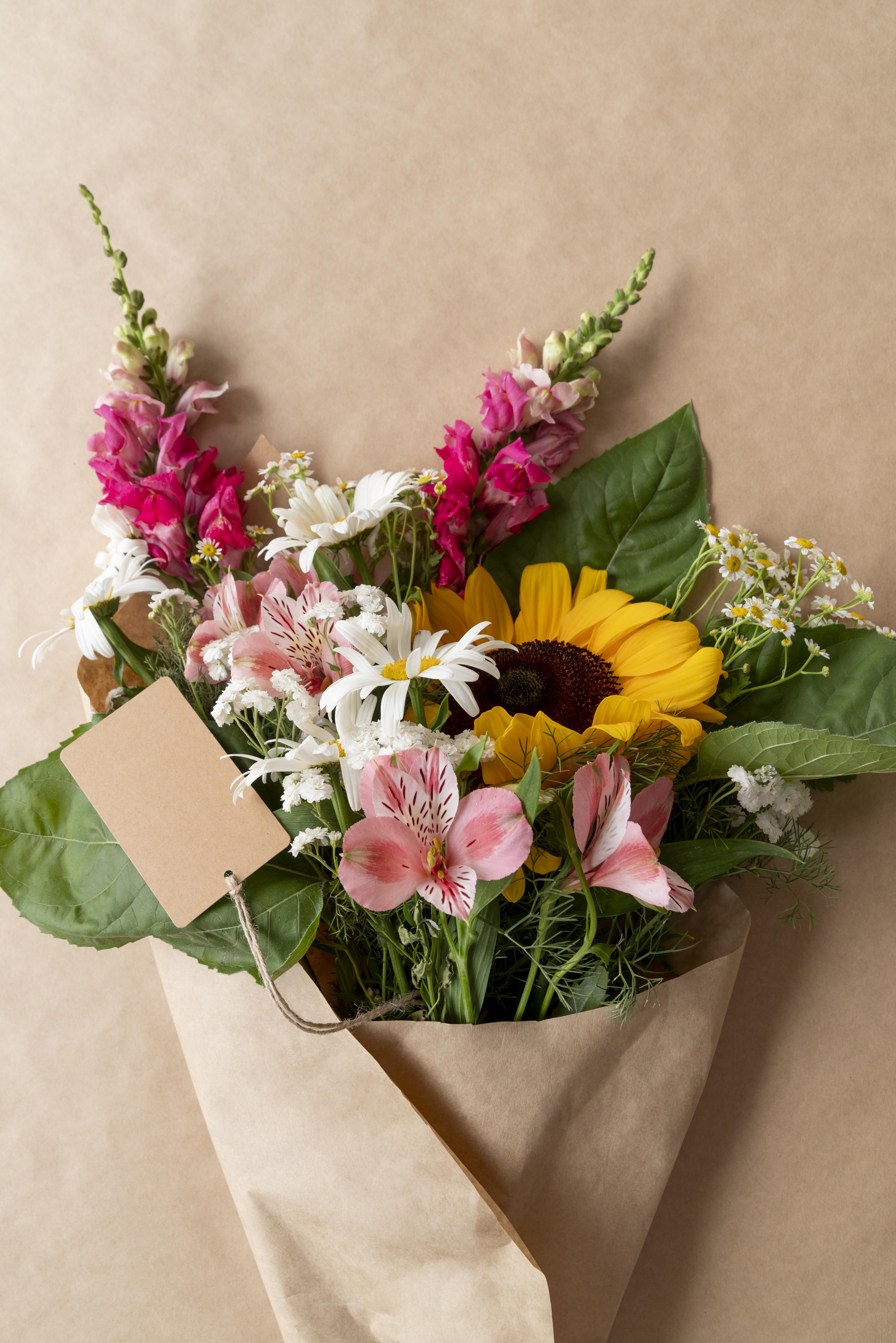 Bouquet of sunflowers, pink alstroemeria, and white daisies in kraft paper