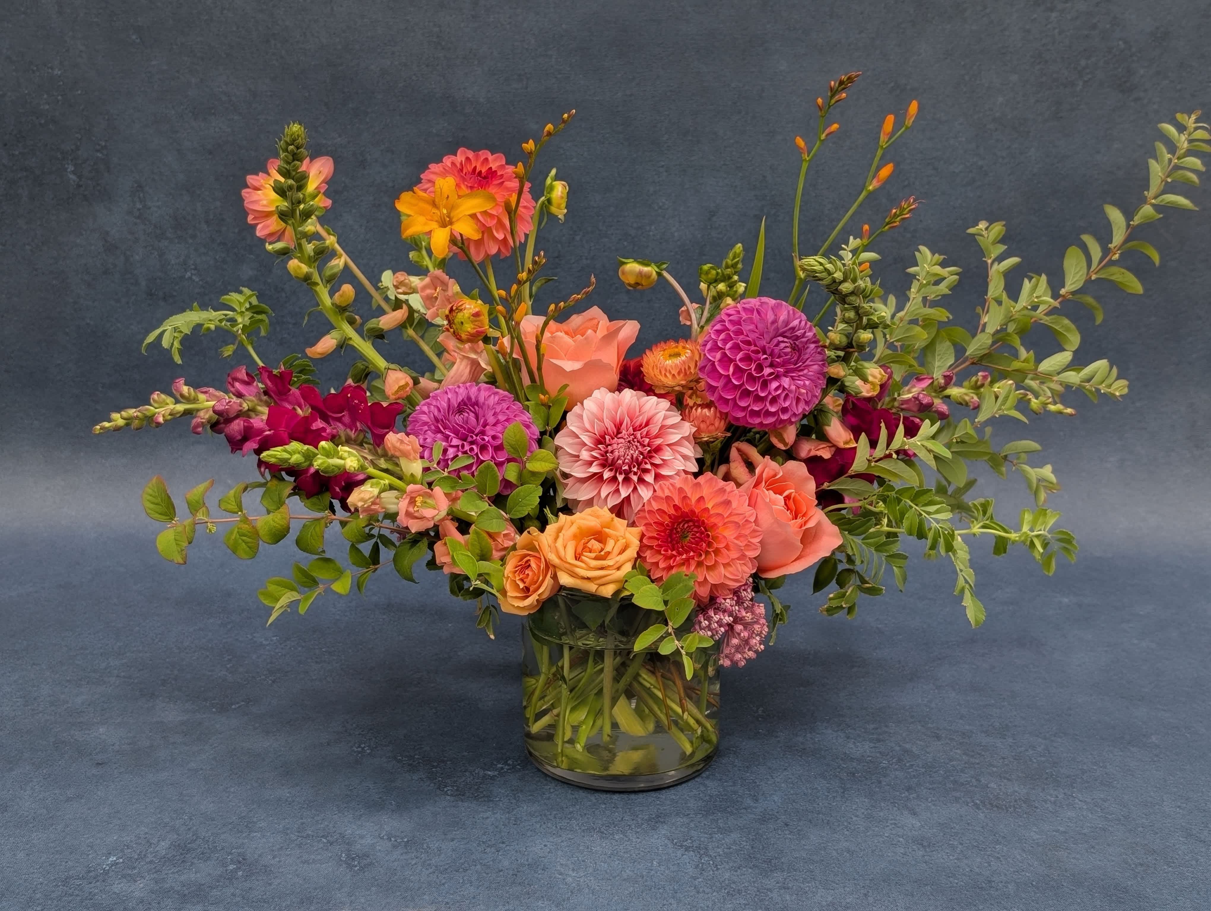 Mixed bouquet of pink, orange, and purple flowers in a glass vase