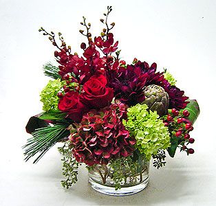 Red roses and burgundy flowers in a clear glass vase
