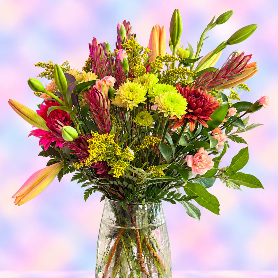 Mixed bouquet of lilies, chrysanthemums, and pink carnations in a glass vase