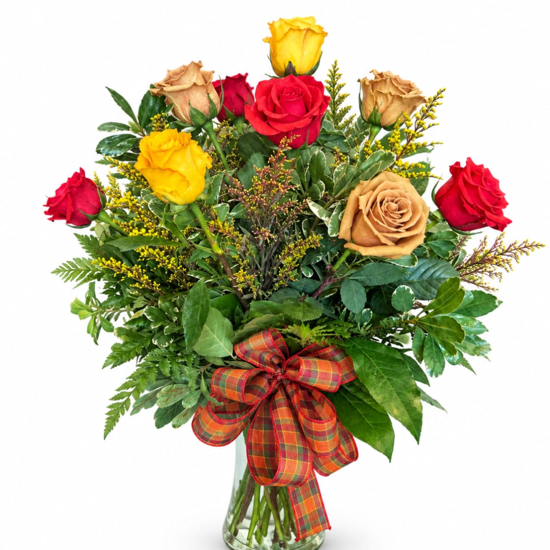 Bouquet of red, yellow, and tan roses in a glass vase with a plaid ribbon