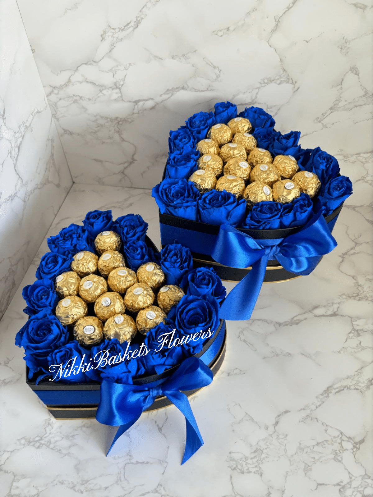 Two blue rose gift boxes filled with gold-wrapped chocolates and ribbon bows