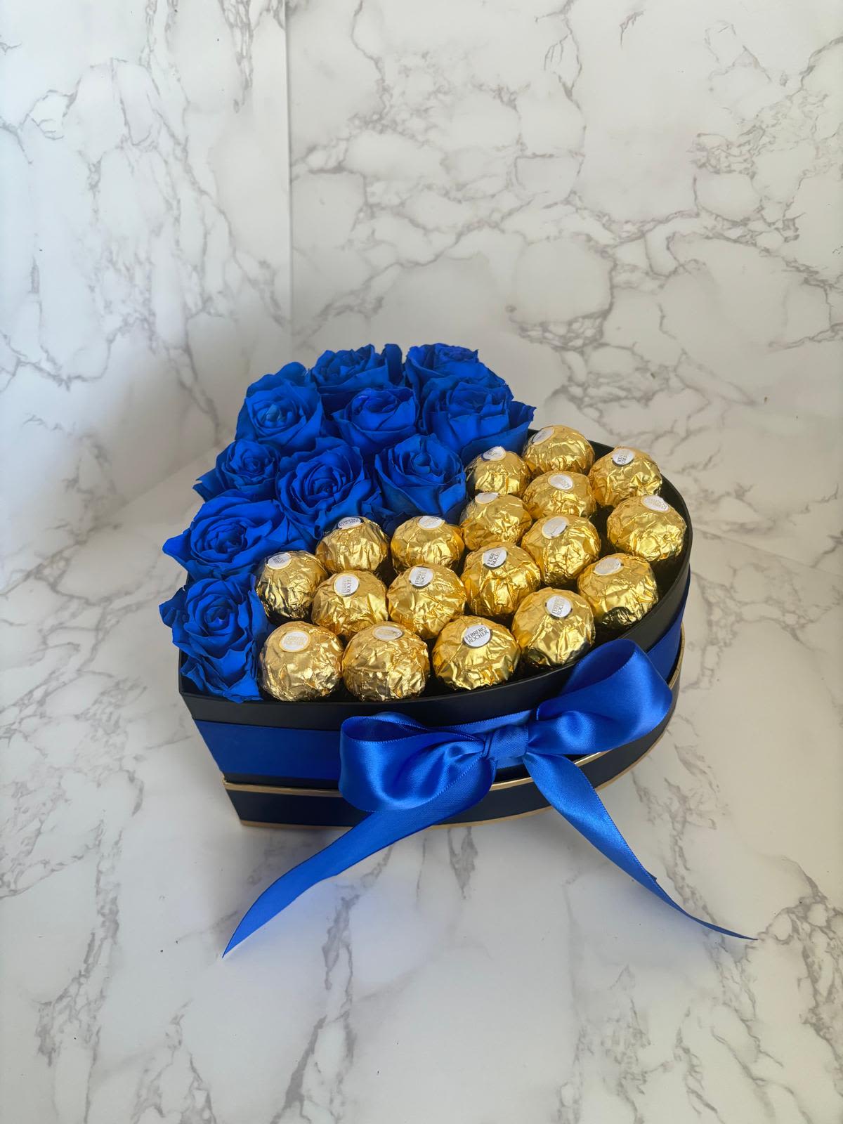 Heart-shaped box with blue roses and gold-wrapped chocolates tied with a blue ribbon
