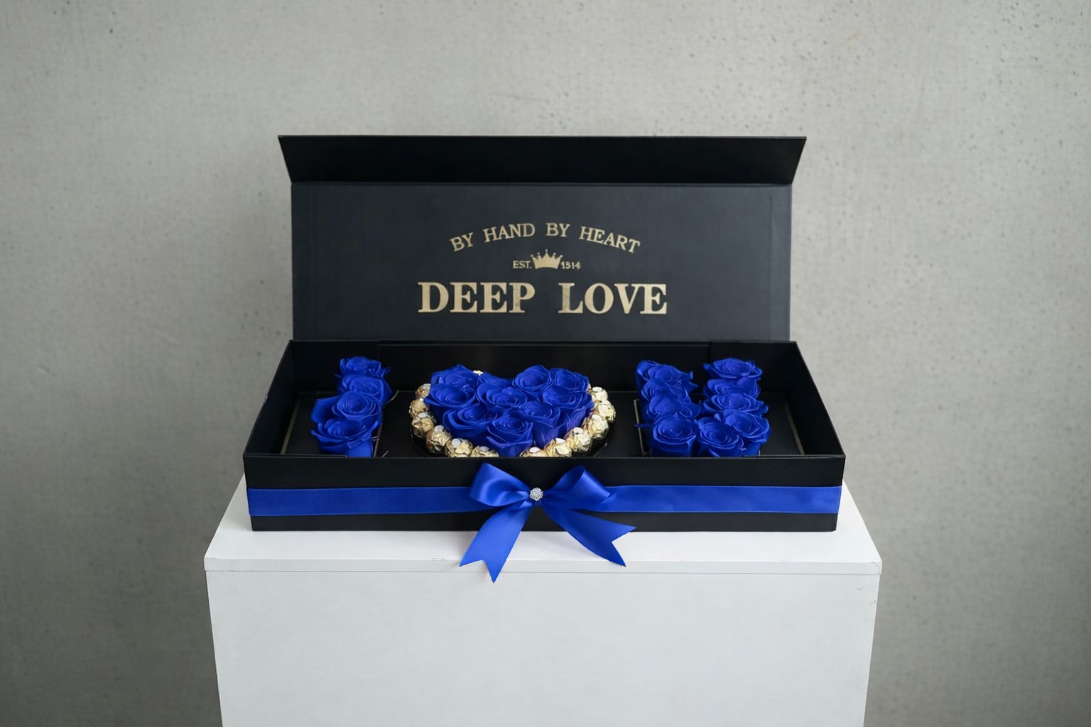 Blue roses arranged in a black gift box with a ribbon bow