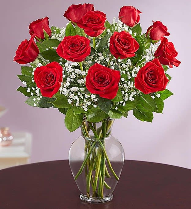 Red roses arranged in a clear glass vase with baby's breath