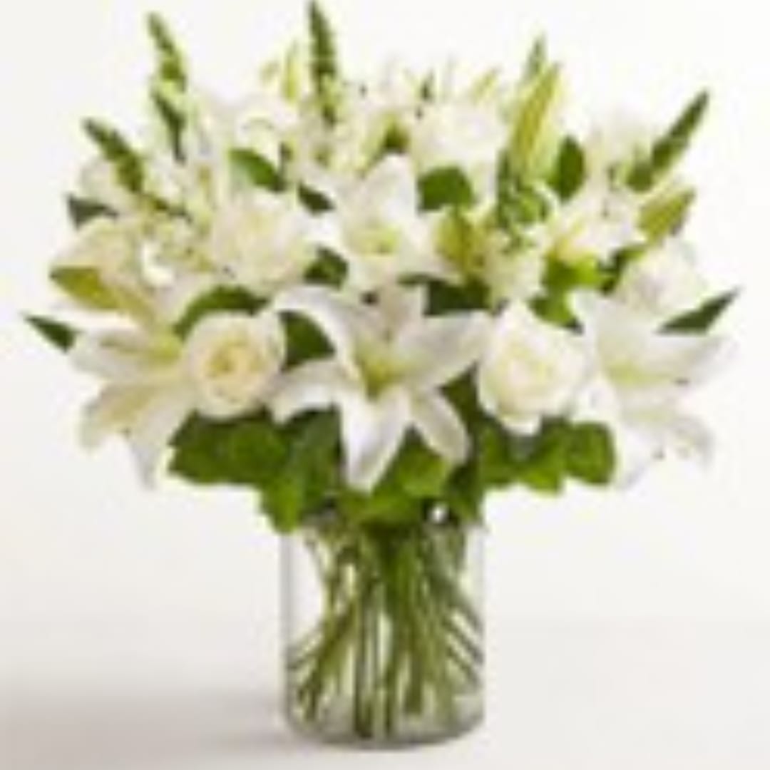 White lilies and roses arranged in a clear glass vase