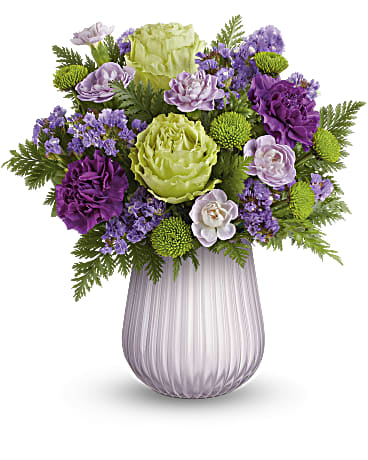 Purple and green floral arrangement in a ribbed glass vase