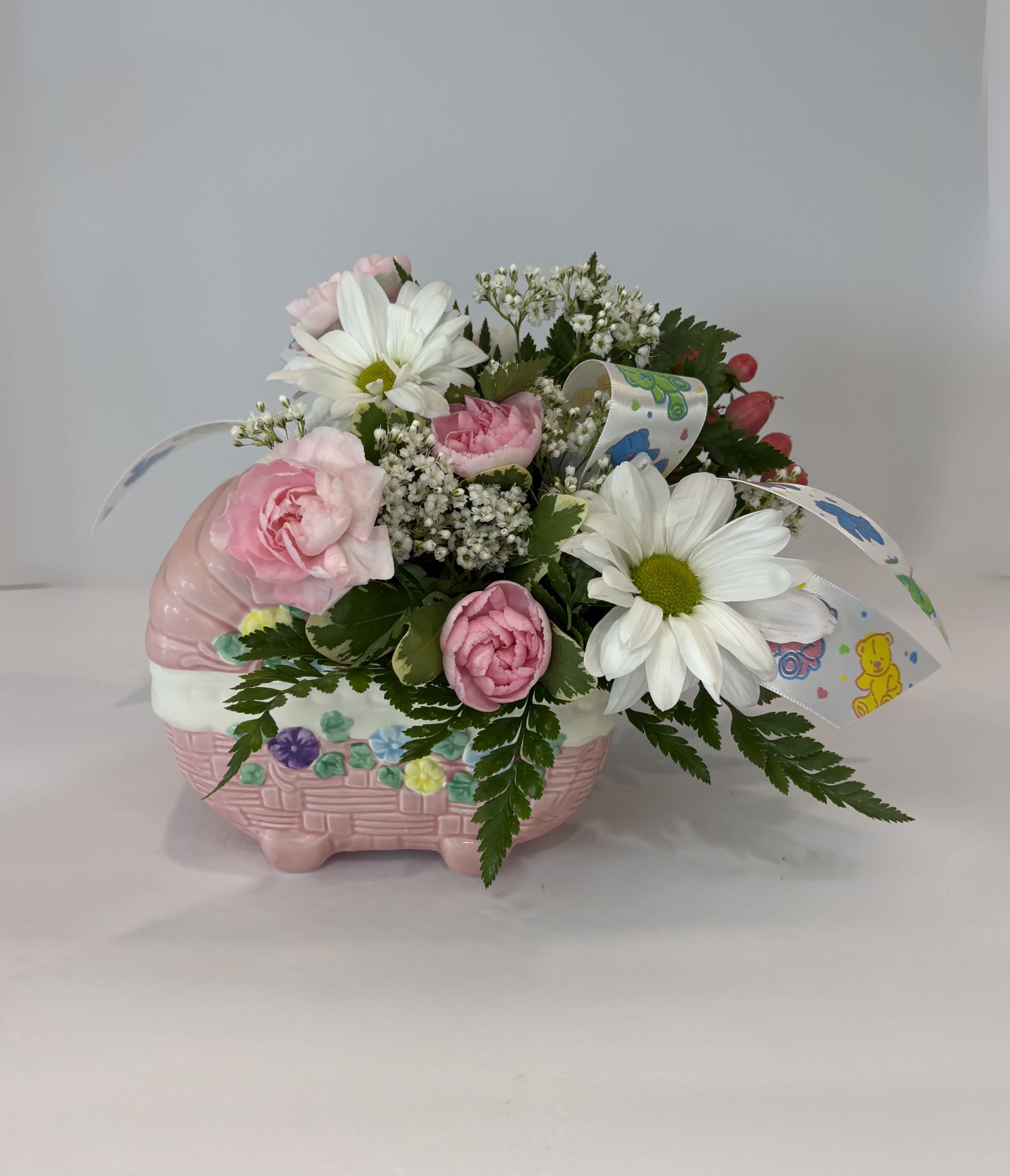 Pink and white flowers arranged in a pink basket-shaped container