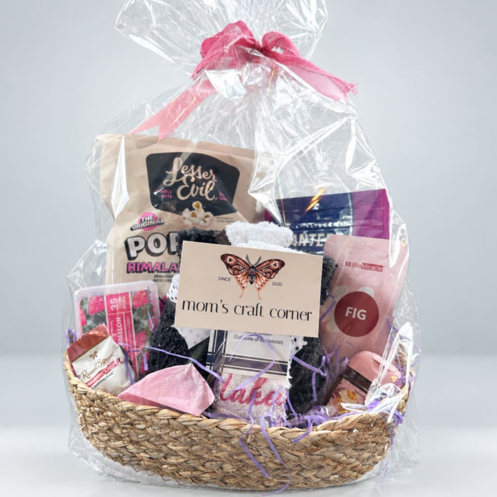 Gift basket with assorted packaged items wrapped in clear cellophane and tied with a pink ribbon